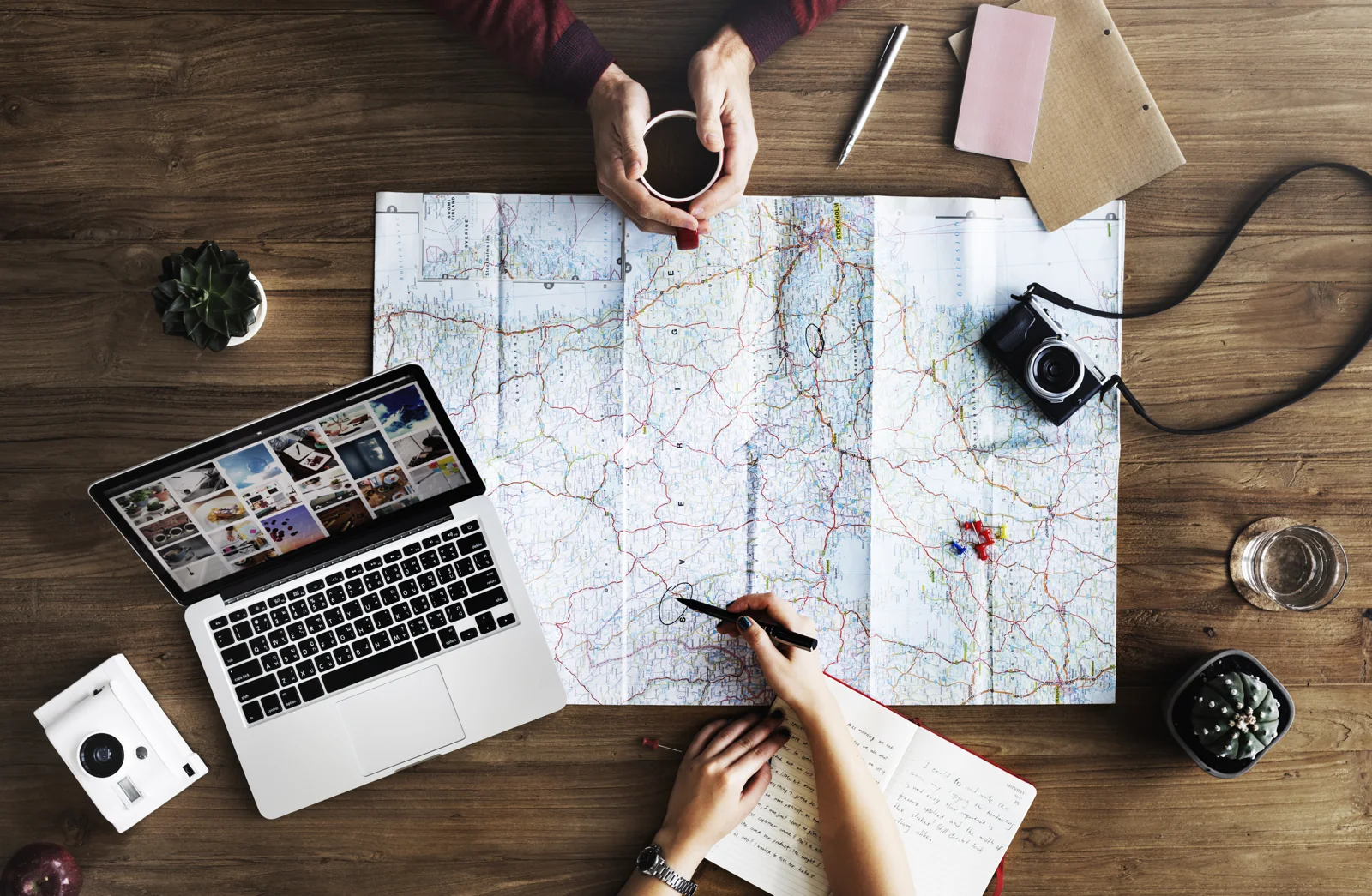 Carte, ordinateur et carnet sur une table pour préparer un voyage et consulter des idées de visites